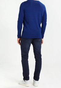 Marineblå långärmad skjorta i en åtsittande design, tillverkad av texturerat stickat material, i par med mörkblå slim fit-byxor och vita sneakers.