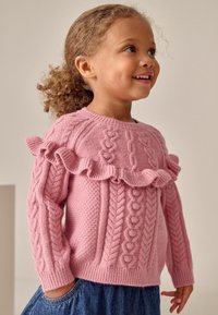 Pulover roz tricotat, prezentând modele de cablu, un corp texturat și detalii în volane la guler. Manșetele și tivul ribbate completează designul.