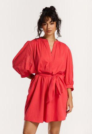 Rotes kurzes Kleid aus leichtem Stoff. Es hat einen Knopfkragen, gepuffte Ärmel und eine gebundene Taille für eine lockere Passform.