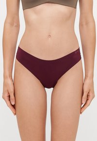 Perizoma borgogna a vita bassa caratterizzato da un tessuto morbido, un design minimalista e accenti del logo discreti sulla cintura.