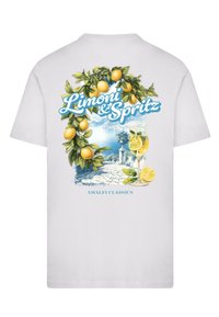 Camiseta blanca con un gráfico colorido de limones, una vista costera y un cóctel, con "Limoni & Spritz" en texto azul.