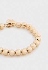 Pulseira de contas em tom dourado, featuring contas esféricas lisas e refletivas, e um fecho tipo toggle para um fecho seguro.