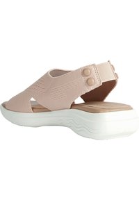 Sandal in tessuto rosa con ampia apertura, fascia elastica e due bottoni decorativi, poggiata su una suola bianca imbottita con un motivo ondulato.