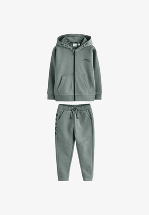 Børns grå hættetrøje med lynlås foran og lommer samt matchende joggingbukser med elastisk talje og sideløbende tekst.