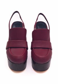 Scarpe con plateau bordeaux con tomaia in pelle liscia e ampia fascia sul collo del piede, caratterizzate da una suola testurizzata simile al legno nero.