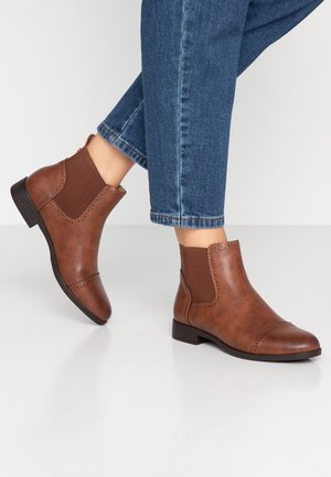 Stivaletti marroni alla caviglia con fasce elastiche laterali, rifiniti in pelle liscia, cuciture decorative e tacchi bassi a blocco, abbinati a denim.