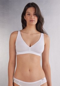 Sostenible inalámbrico blanco con diseño de cuello en V, fabricado con una tela suave, que presenta tirantes anchos y una construcción sin costuras para mayor comodidad.