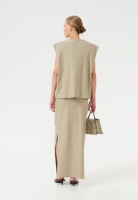 Beidzam, bez piedurknēm, brīvi pieguļošs topiņš, apvienots ar atbilstošu maxi svārku ar sānu šķēlumu. Aksesuāri ietver rakstainu rokassomu.