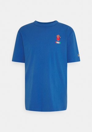 Blå t-shirt med korte ærmer med en lille rød tegneserie dåse og farverigt Puma-logo på venstre bryst og et lille Puma-mærke på venstre ærme.