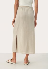 Jupe maxi plissée beige avec une fente sur le côté. Fabriquée à partir d'un tissu doux et texturé, elle est dotée d'une taille élastique et d'une coupe décontractée.