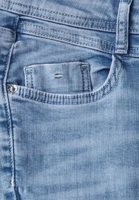 Jeans de mezclilla azul claro que presentan un pequeño bolsillo frontal visible y detalles de costura estándar. La tela muestra ligeras variaciones en la textura.