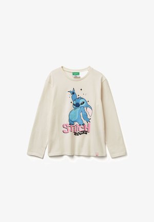 Maglietta a maniche lunghe di colore crema con grafica di un personaggio cartoon blu e la scritta "Stitch Rocks" in rosa e nero. Materiale in cotone leggero.