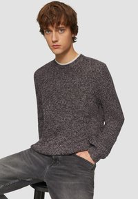 Gebreide trui in donkergrijs met een gestructureerd patroon, ronde halslijn en lange mouwen, gecombineerd met vervaagde grijze jeans.