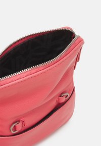 Borsa in pelle rosa con chiusura a zip, dotata di una superficie testurizzata, fodera nera a motivo e dettagli in metallo sui lati.