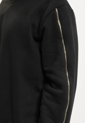 Schwarzer Kapuzenpullover mit strukturiertem Stoff und einem silbernen Reißverschlussakzent am linken Ärmel, mit Rundhalsausschnitt und gerippten Bündchen.