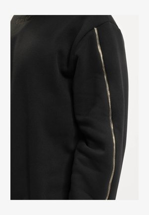 Sort sweatshirt med struktureret stof og en sølv lynlåsdetalje på venstre ærme, med rund halsudskæring og ribbede manchetter.