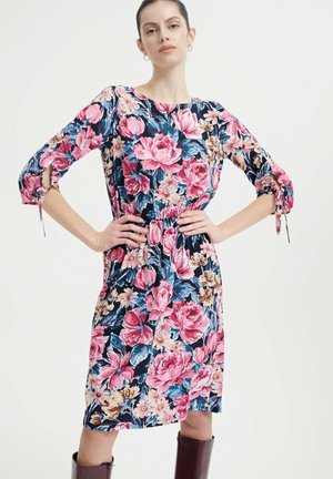 Blumenkleid mit großen rosa und blauen Blumen auf einem marineblauen Hintergrund. Dreiviertelärmel, elastischer Bund und Krawattendetails an den Ärmeln.