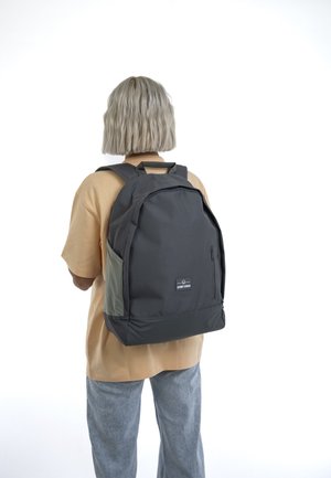 Gray backpack with dark gray accents and a side pocket, made from durable fabric. Features a logo patch and dual shoulder straps.