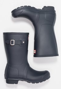 Bottes de pluie en caoutchouc noir avec une semelle robuste, un détail de boucle sur le côté et une finition mate lisse. Adaptées aux conditions humides.