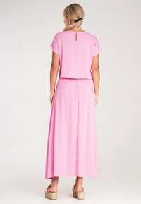 Różowy dwuczęściowy zestaw składający się z topu na krótki rękaw i maxi spódnicy. Miękka, teksturowana tkanina z detalem na plecach przy dekolcie.