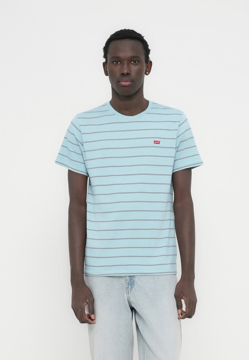 Ανοιχτό μπλε βαμβακερό μπλουζάκι με οριζόντιες γκρι ρίγες, στρογγυλή λαιμόκοψη, κοντά μανίκια και κόκκινο λογότυπο Levi's στην πάνω πλευρά του στήθους.