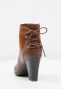 Bottine en cuir marron avec une tige en daim, design à lacets, bout rond et talon bloc haut. Comprend du matériel métallique et une semelle texturée.