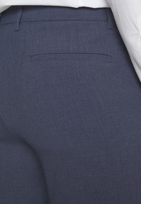 Navyblauwe broek van gestructureerde stof, met een enkele achterzak en een gladde tailleband. Slim fit met subtiele stiksel details.