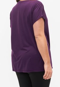 Short-sleeve purple t-shirt with a relaxed fit, smooth texture, and curved hem. Fabric is lightweight and stretchy, designed for comfort.