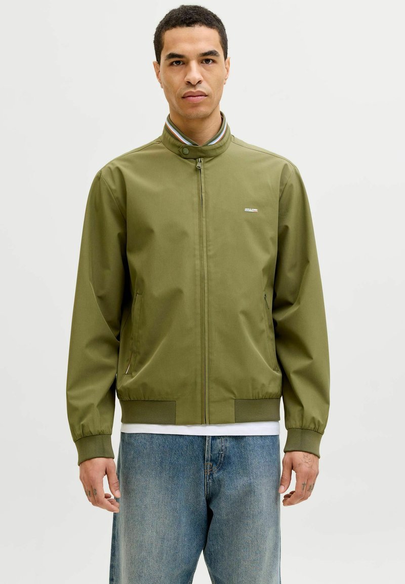 Olivovo zelená bunda na zips s vysokým golierom, elastickými manžetami a lemom; obsahuje dve bočné vrecká a malé logo na hrudi.