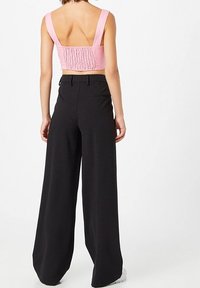 Rosa croppad topp med smockad rygg, parat med svarta vida byxor med en subtil rutmönster och hög midja.