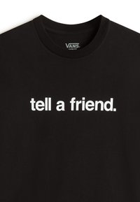 Sort bomulds t-shirt med rund hals, der har fed hvid tekst "fortæl en ven." og en løs pasform.