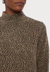 Pull à col roulé en tricot avec un motif texturé dans des tons de noir et de marron, doté d'un col près du corps et d'un tissu doux.