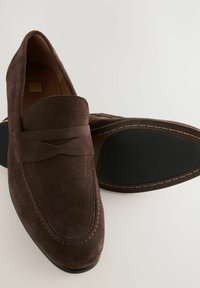 Mocassins en suede marron avec un subtil détail de couture et une doublure en cuir lisse. Présentent un bout arrondi et une semelle en caoutchouc pour une meilleure traction.