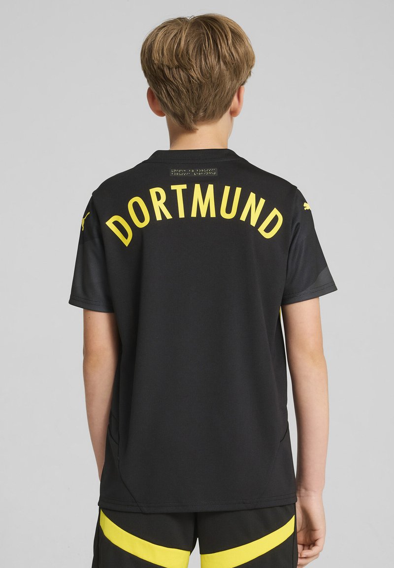 Jersey deportivo negro con el texto amarillo "DORTMUND" en la parte posterior, de manga corta, con cuello y aberturas laterales. Tejido ligero y sin patrón.