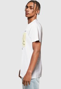 Hvid bomulds t-shirt med et gult grafisk print på forsiden. Enkel crew neckline, korte ærmer, afslappet pasform og let tekstur.