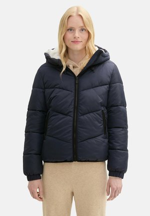 Giacca puffer navy con cappuccio, caratterizzata da un design a trapunta, zip frontale e dettagli neri. Tessuto testurizzato con polsini elastici.
