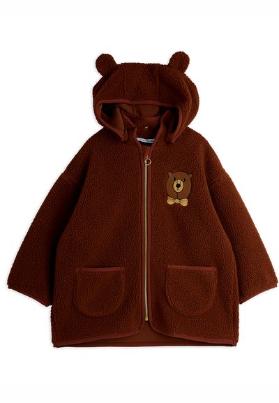 Brun fleece barnejakke med bjørneører på hetten, frontglidelås, to lommer, og et bjørneansikt med sløyfe på brystet.