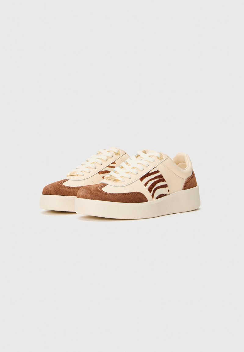 Chaussure avec une tige en cuir crème et des accents en daim marron. Présente un panneau à motif zèbre, un bout rond et un design à lacets. Semelle plate en caoutchouc.