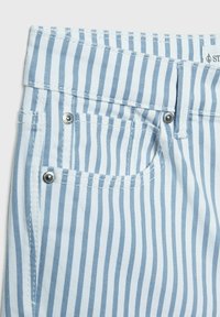 Jasnoniebieska i biała materiałowa tkanina w paski z zbliżeniem na pasek, z metalowymi elementami i małą przednią kieszonką.