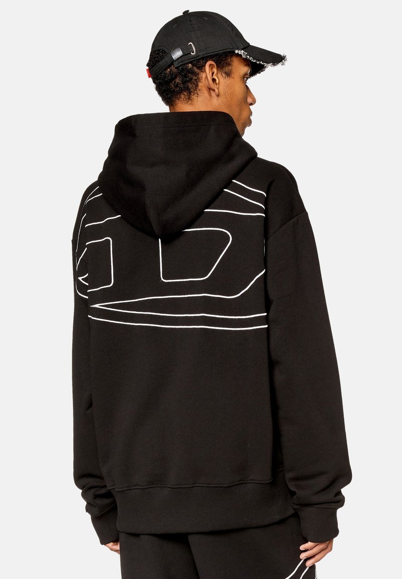 Sudadera negra con diseño de líneas blancas en la parte posterior, hecha de tela suave. Cuenta con una capucha y puños acanalados. Combinada con una gorra negra.