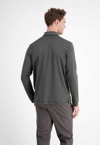 Koszulka polo z długim rękawem w ciemnoszarym materiale z kołnierzykiem, posiadająca prosty dół i boczne rozcięcia dla swobody ruchów.