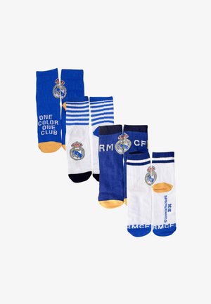 Quatre paires de chaussettes : bleu avec des accents dorés, blanc avec des orteils bleus, rayées bleues, toutes arborant le logo du Real Madrid et des motifs textuels.