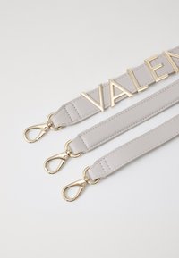 Pelēka ādas siksna ar trim regulējamiem garumiem. Iespējas zeltainā krāsā un "VALENTINO" logo treknajiem burtiem. Gluda faktūra.