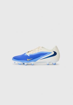 Chaussure de football Nike bleue et beige avec des crampons bleus, un logo swoosh jaune et des lacets, sur un fond blanc uni.