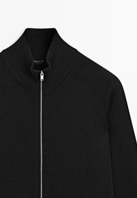 Maglione nero in maglia con zip frontale e collo alto. Presenta una trama a coste sulle spalle e sui lati, etichetta con marchio sul collo.