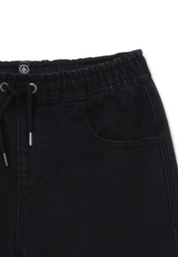 Svarta joggerbyxor med elastisk midja, snörning, framfickor och mjukt, texturerat tyg. Har metalliska detaljer.