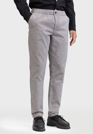 Grau karierte Hose mit einem bequemen elastischen Bund und einem Knopfverschluss, mit geradem Bein und Seitentaschen. Schwarze Schuhe.