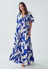 Abito maxi in stampa floreale blu e bianca, con maniche corte, vita con laccetto e orlo a strati. Realizzato in tessuto leggero.