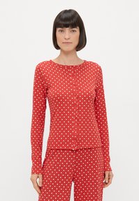 Czerwony top z długim rękawem w białe kropki, okrągły dekolt i zapięcie na guziki z przodu. Miękka tkanina z prążkowanym wzorem. W komplecie z pasującymi spodniami piżamowymi.