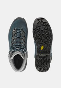 Buty turystyczne z niebiesko-szarym zamszowym wierzchem, szarym gumowym detalem oraz teksturowaną czarną podeszwą Vibram z wielokierunkowym bieżnikiem zapewniającym przyczepność.